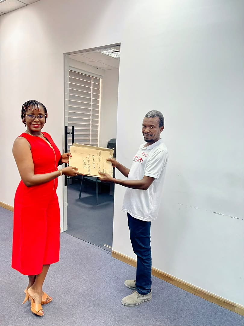 Zuri Motors staff handing over vehicle documents to a customer