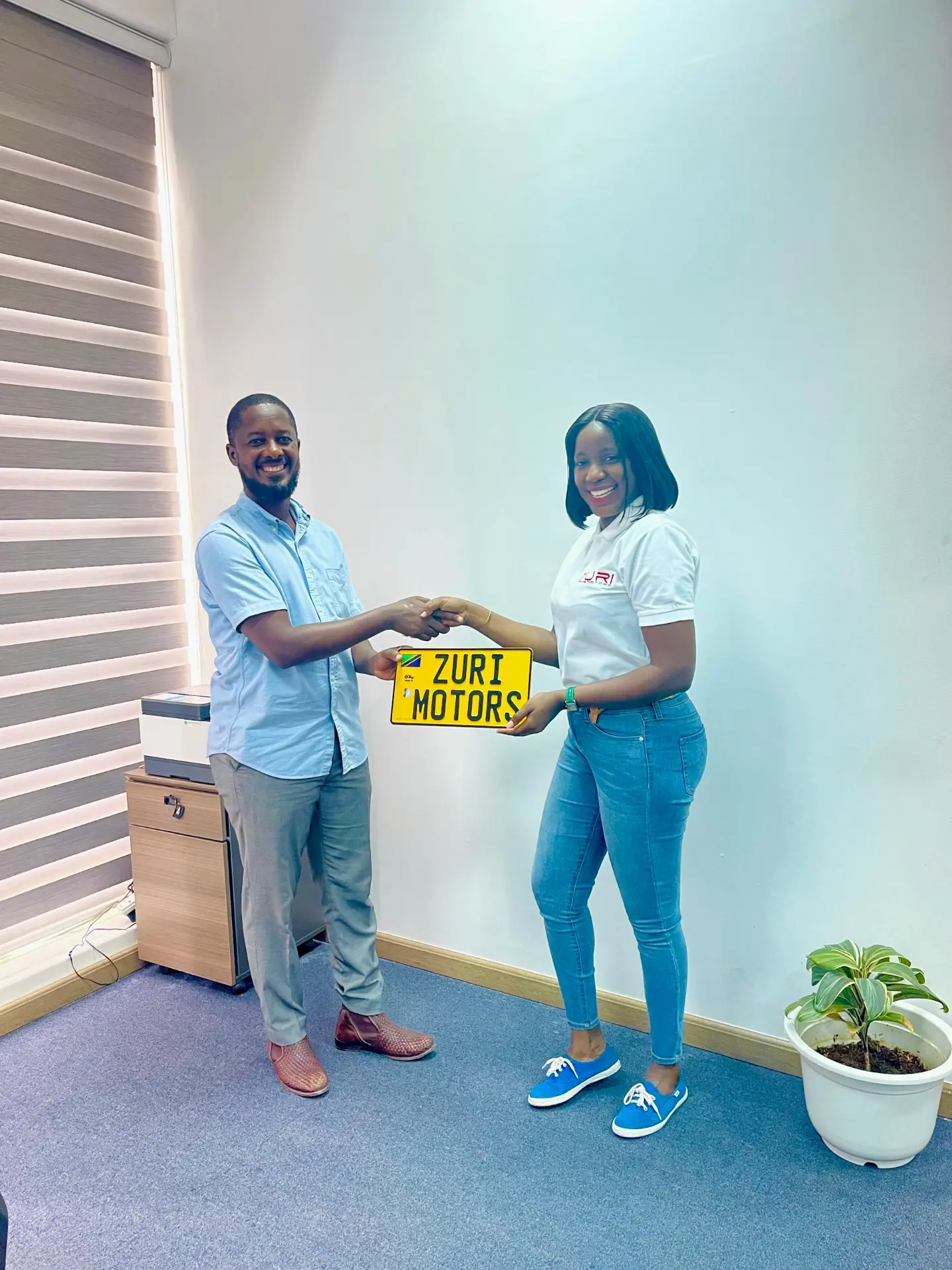 Zuri Motors staff handing over a Tanzanian number plate to a customer at the Dar es Salaam office